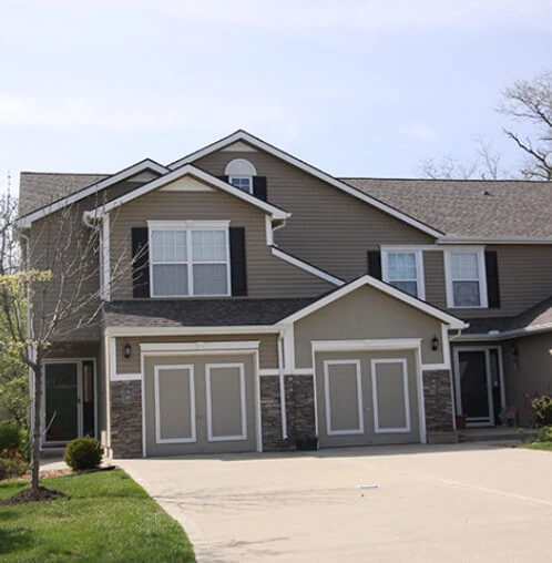 A multi-family home with a new asphalt shingle roof and new gutters installed by Bill West Roofing.