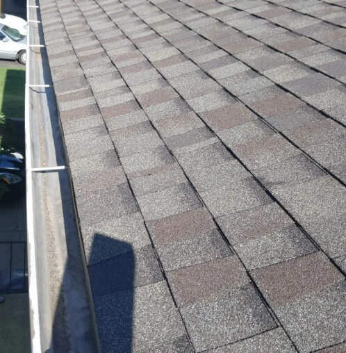 A home in Kansas City with a new shingle roof and gutters installed by Bill West Roofing.