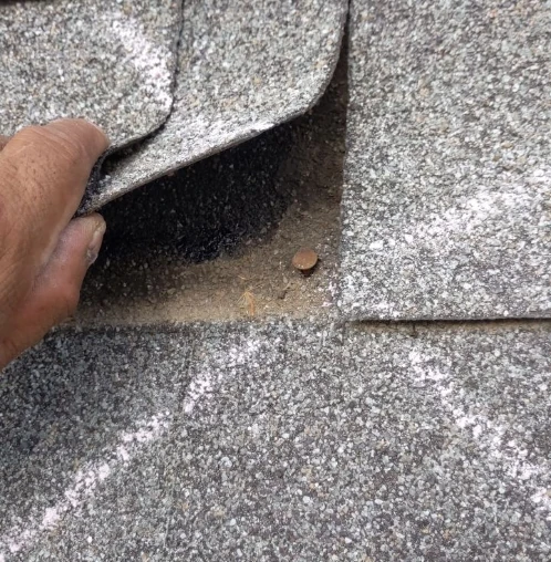 A damage roof showing where the nail has separated from the shingle during a storm or high winds.