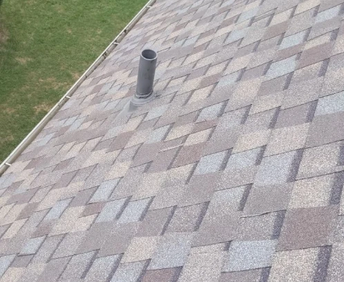 An asphalt shingle roof and a pipe boot with gutters on the home.